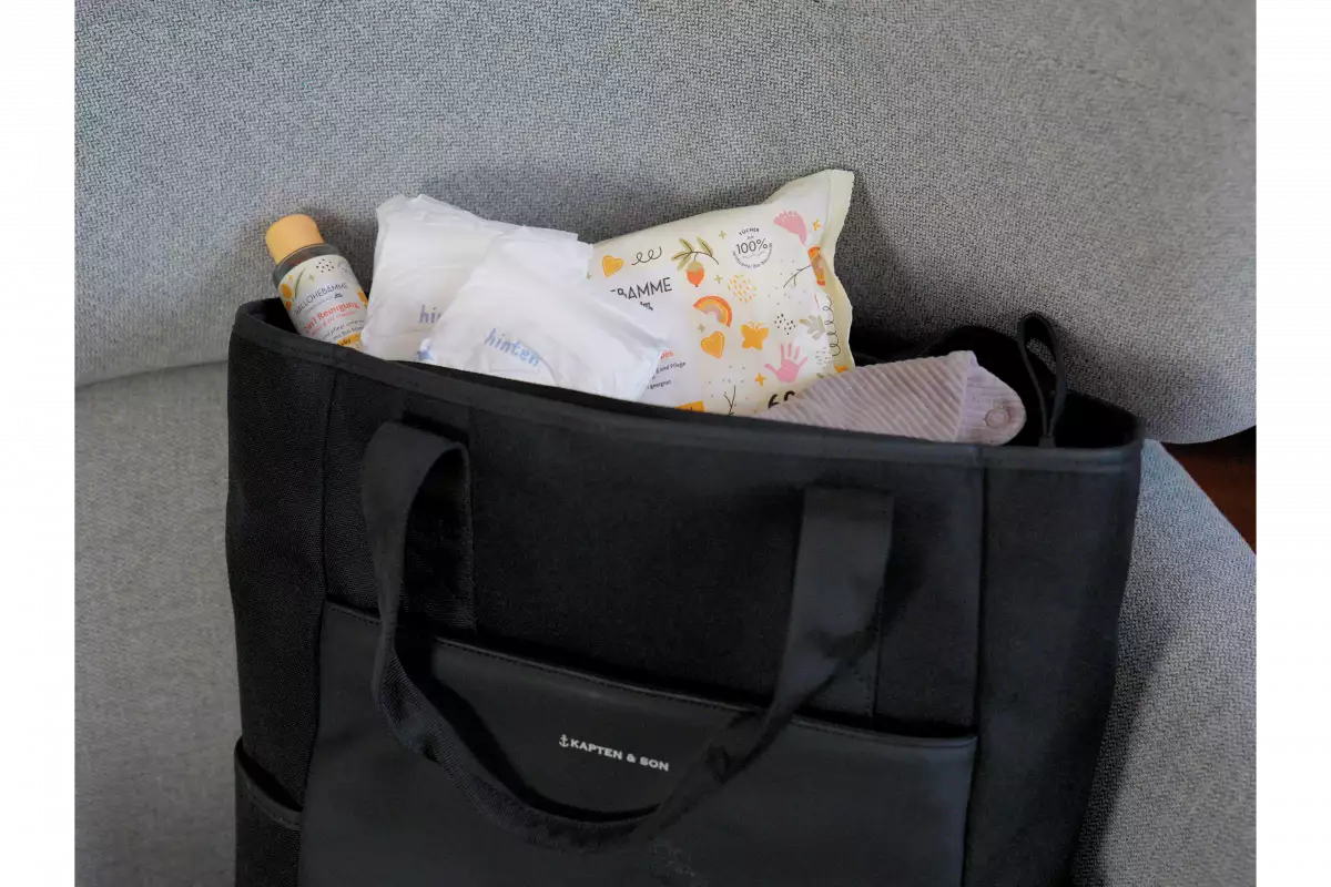 Ein Wickelrucksack, in dem sich Feuchttücher, ein Lätzchen, Windeln und eine sanfte Reinigung befinden.