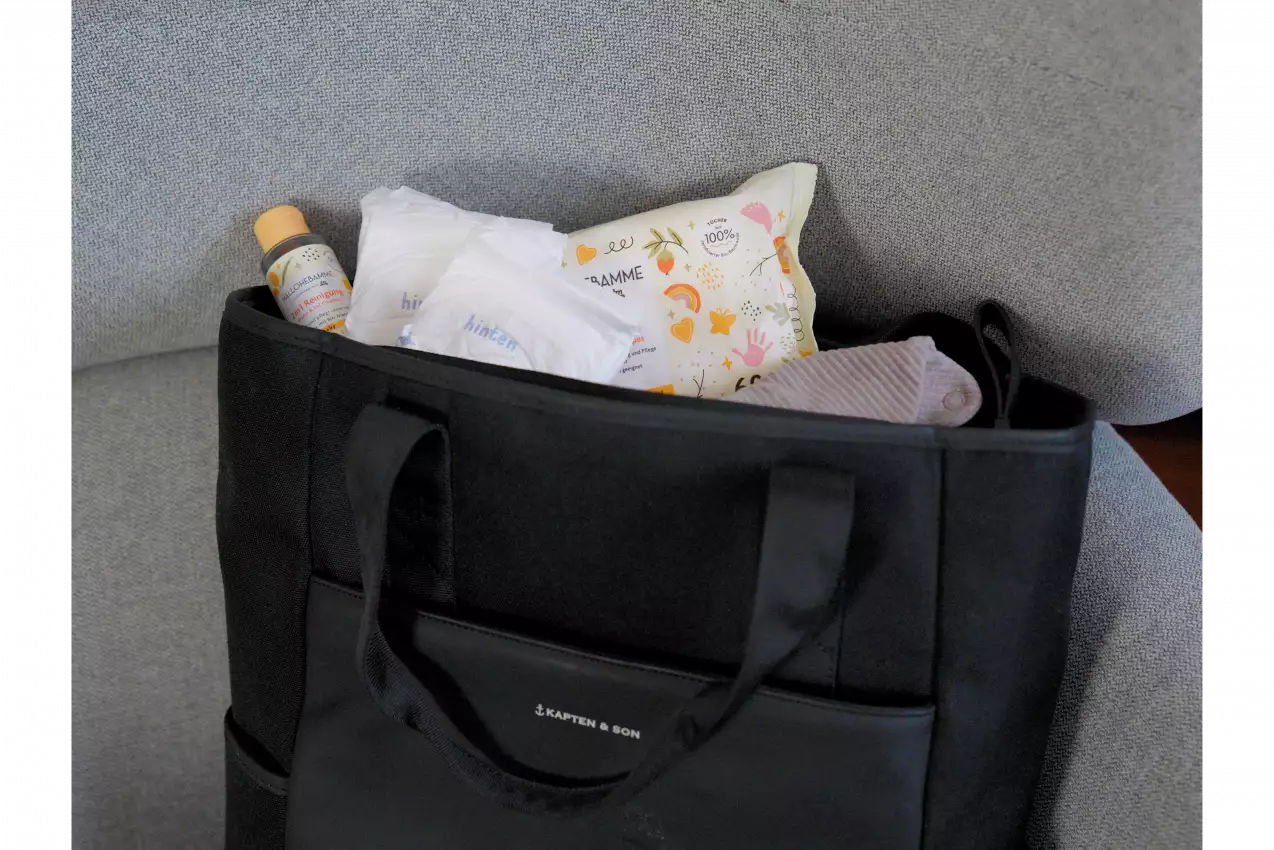 Ein Wickelrucksack, in dem sich Feuchttücher, ein Lätzchen, Windeln und eine sanfte Reinigung befinden.